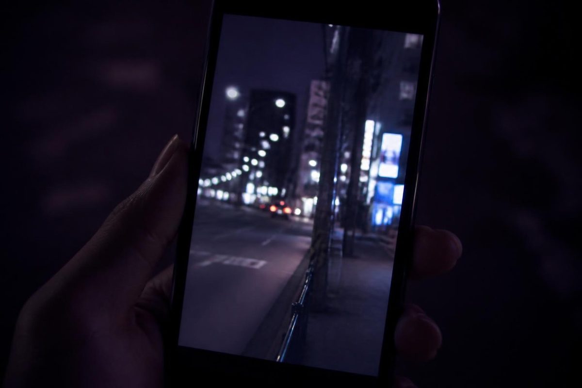 夜の街でスマートフォンを構える手元