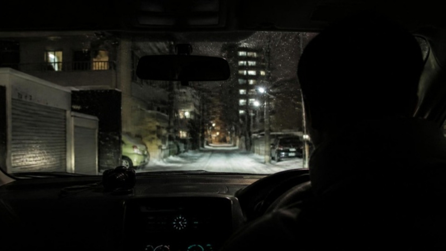 冬の夜、車内から住宅街を見張る調査員の後ろ姿（イメージ）