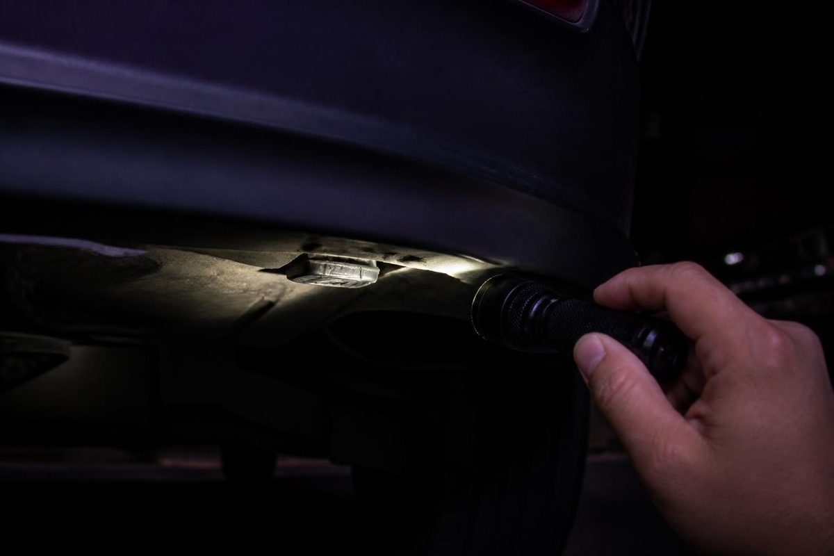 車の下を懐中電灯で照らす手元