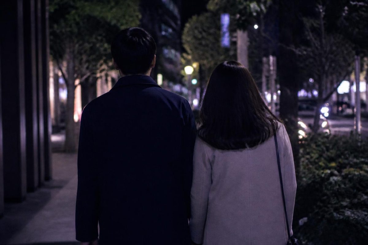 夜の街を並んで歩く男女の後ろ姿